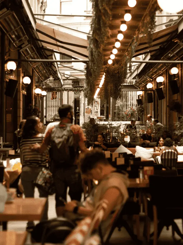 A barber works on a client's beard under a bright ring light in a cozy studio setting.